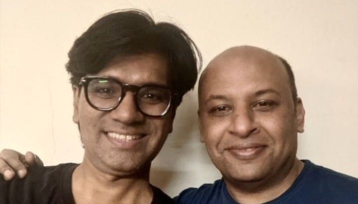 Two smiling men pose together in a close-up portrait