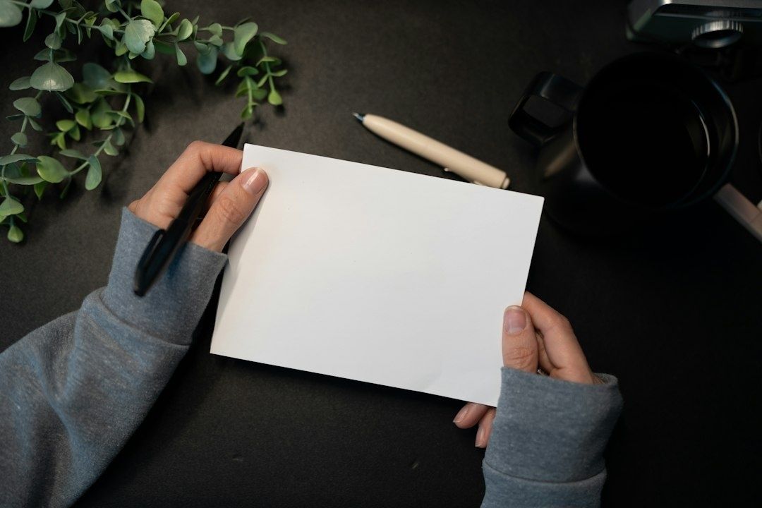 Person holding a blank paper and pen at a minimalist desk